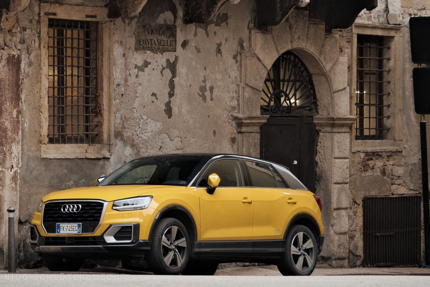 Gelber Audi Q2 mit schwarzem Dach vor der verwitterten Steinfassade eines alten Hauses im Vicolo Fontanelle