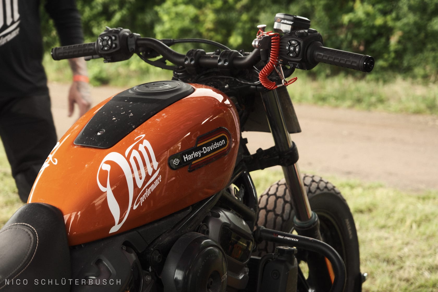 Oranger Tank einer Harley-Davidson im Flat-Track-Stil mit Don-Performance-Schriftzug und roter Spiralleine am Lenker